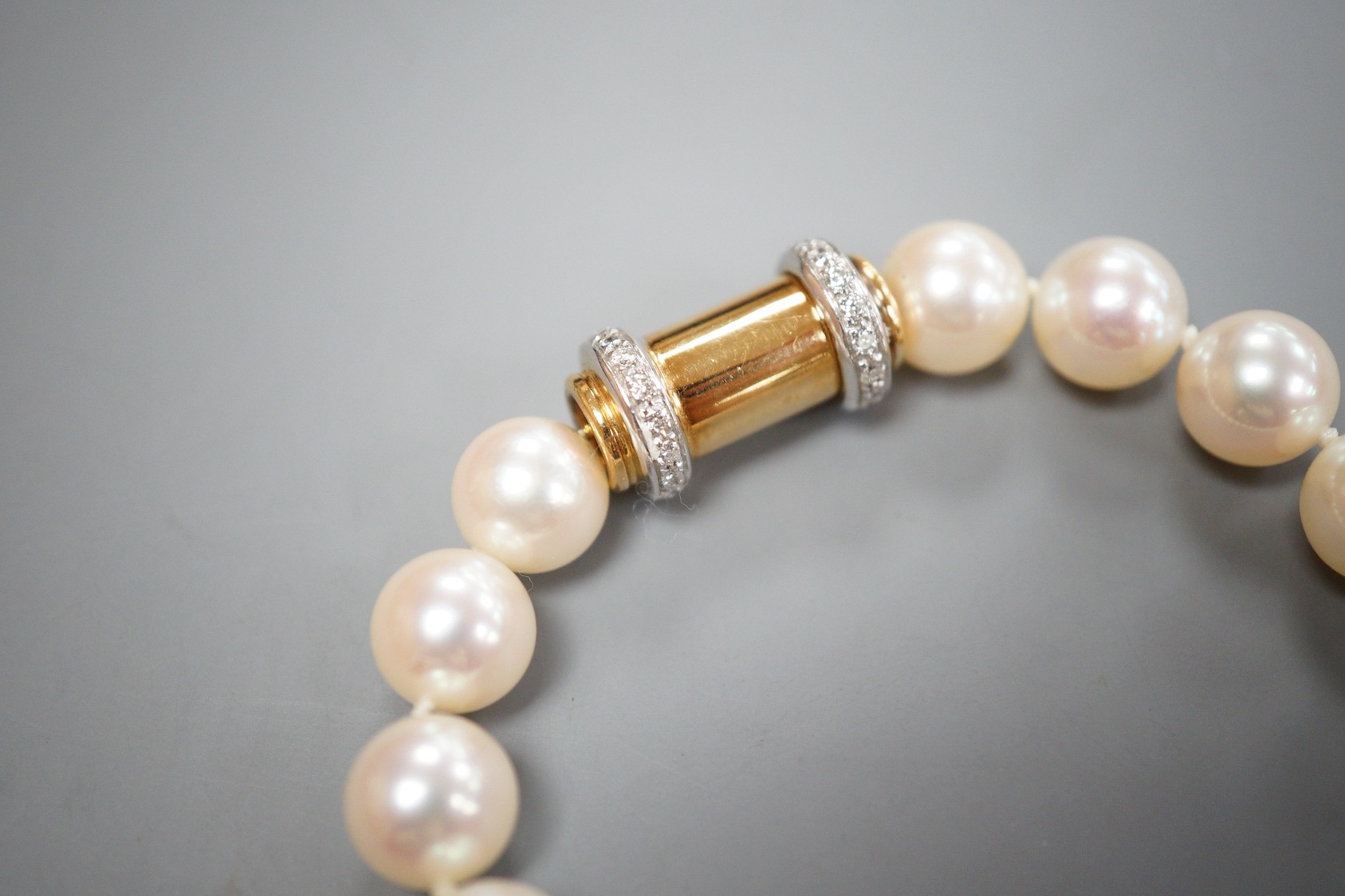 A cased modern single strand Akoya cultured pearl necklace, with diamond chip set 750 yellow metal barrel shaped clasp, retailed by Musson, 43cm, gross weight 59 grams